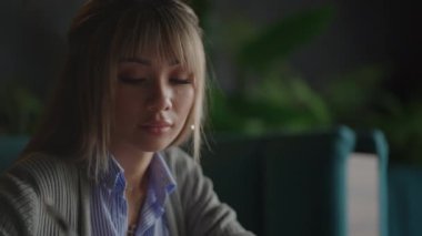 Ofisteki ahşap masaya yerleştirilmiş kahve ve dizüstü bilgisayarlı güzel, gülümseyen Asyalı iş kadını. Evden işe giderken e-postaları kontrol eden ya da araştırma yapan kadın