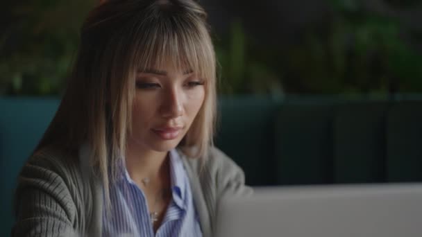 Young Beautiful smiling Asian business woman holding a coffee and laptop Placed at the wooden table at the office. Woman checking mail or researching while telecommuting — Vídeo de Stock