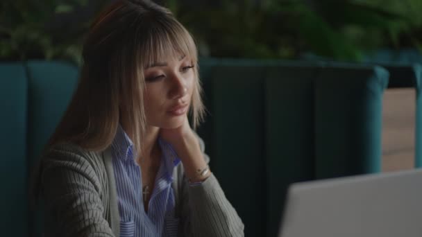 Portrait of a beautiful, young and attractive Asian woman is sitting and looks worried and serious as she broods in front of her laptop computer during the day. — Vídeo de Stock