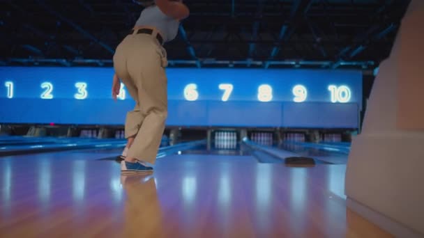 The camera follows one woman throwing a bowling ball on the playing track and jumping around rejoicing in the downed pins. One man bowling in slow motion — Stock video