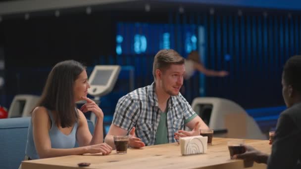 A multi ethnic group of friends in a bowling club are chatting at the table and smiling — Stok video