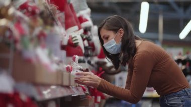 A woman in a protective mask in a jewelry store and garlands with toys for Christmas trees and at home. Christmas garlands and decor
