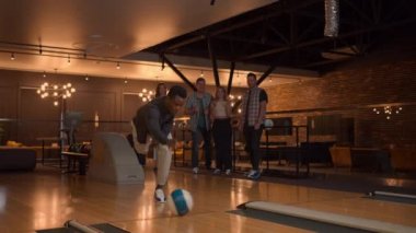 A black man makes a throw in a bowling club and enjoys emotionally knocking out pins with a ball