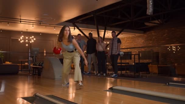 A woman makes a throw in a bowling club and enjoys emotionally knocking out pins with a ball — Stock Video