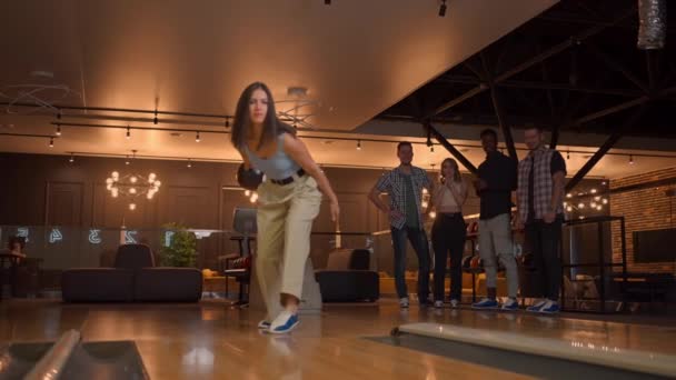 Multi ethnic Group of friends in a bowling club a woman throws a ball and knocks out a strike — 비디오