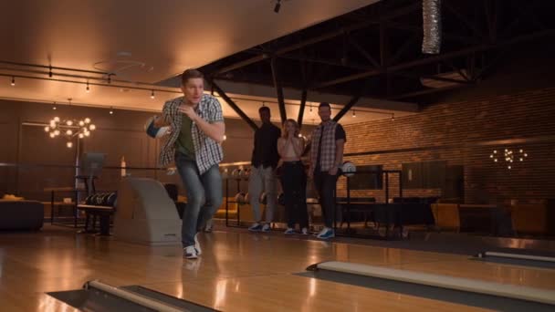 A man makes a throw in a bowling club and rejoices emotionally knocking out pins with a ball — Stock video