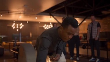 Multi ethnic Group of friends in a bowling club, Portrait of a black man throws a ball and knocks out a strike