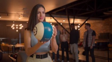 Multi ethnic Group of friends in a bowling club, Portrait of a brunette woman throws a ball and knocks out a strike