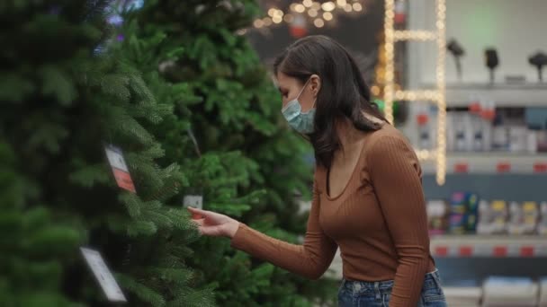 A woman in a protective mask in a jewelry store and garlands with toys for Christmas trees and at home. Christmas garlands and decor — Wideo stockowe