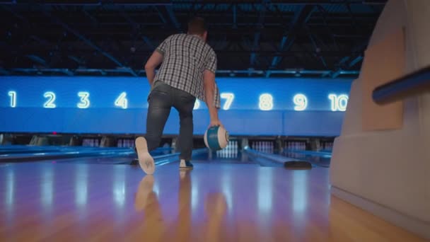 View from the back a man throws a ball and the camera follows him in a bowling club — Stock video