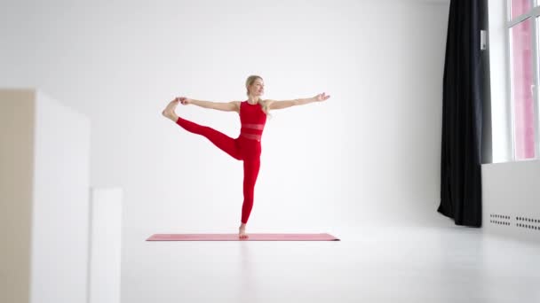 Young attractive girl practicing yoga isolated on white background in red Sportswear . Concept of healthy life and natural balance between body and mental development. Full length – stockvideo