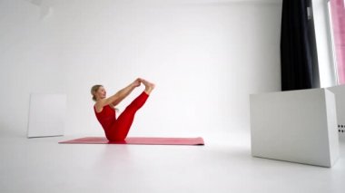 Young woman shows yoga or pilates exercises. Young attractive woman practicing yoga in studio. Girl shows different poses for yoga in white background. Healthy lifestyle, yoga in my heart, sports