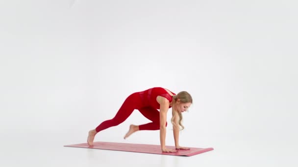 Young attractive girl practicing yoga isolated on white background in red Sportswear . Concept of healthy life and natural balance between body and mental development. Full length — Wideo stockowe