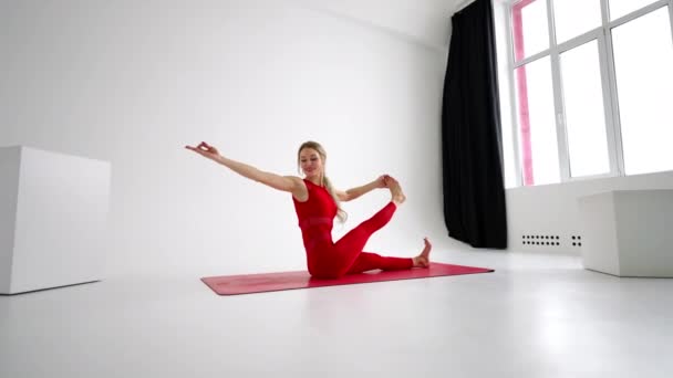 Millennial woman stretching in yoga pose meditation isolated on white background in red Sportswear. Portrait of young female yoga practitioner posing for copy space. 4k — Stockvideo