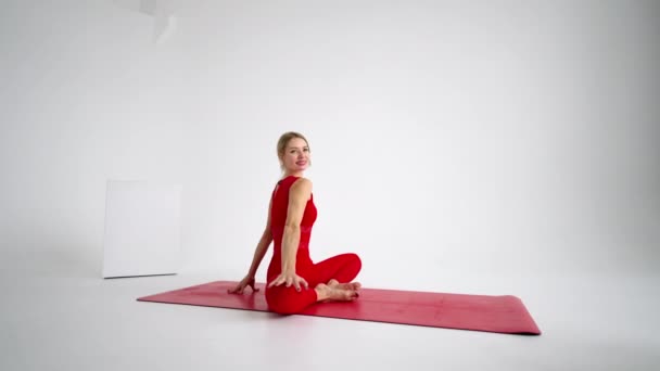 Όμορφη νεαρή γυναίκα φορώντας κόκκινα αθλητικά κάνοντας γιόγκα ή πιλάτες στάση άσκηση, σε λευκό φόντο. — Αρχείο Βίντεο
