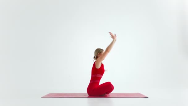 Красива молода жінка в червоному спортивному одязі робить йогу або пілатес вправи позу, на білому тлі . — стокове відео