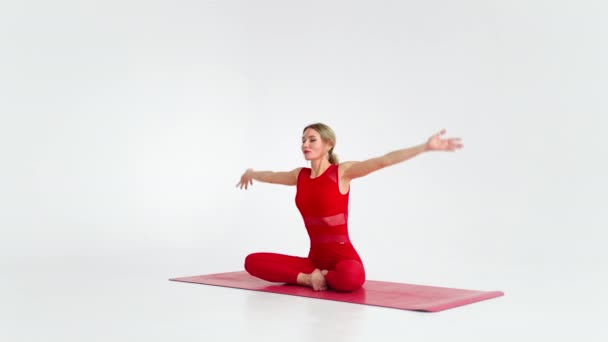 Hermosa joven con ropa deportiva roja haciendo yoga o pilates pose de ejercicio, sobre fondo blanco. — Vídeos de Stock