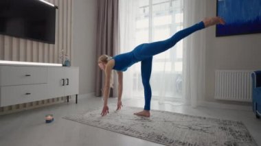 Female performing yoga exercise stretching flexible body lifting hands on mat at home. Sportswoman doing fitness training at living room enjoying physical activity healthy lifestyle