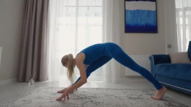 Female performing yoga exercise stretching flexible body lifting hands on mat at home. Sportswoman doing fitness training at living room enjoying physical activity healthy lifestyle