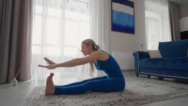 Female performing yoga exercise stretching flexible body lifting hands on mat at home. Sportswoman doing fitness training at living room enjoying physical activity healthy lifestyle — Stockvideo