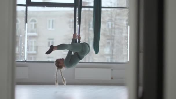 Jonge glimlachende vrouw oefent in de aero stretching swing. Luchtvliegen yoga oefeningen oefenen in groene hangmat in fitness club — Stockvideo