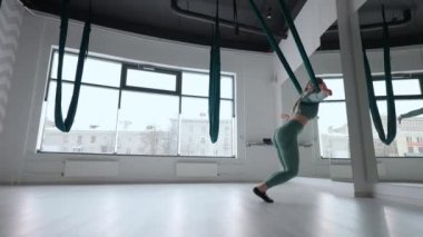 Genç ve güzel bir kadın, salıncakta sallanıyor. Genç bir kadın, hava yogası için hamakta kafasını ters çeviriyor. Odaklanmış olgun bir kadın spor salonunda hava yogası yapıyor.