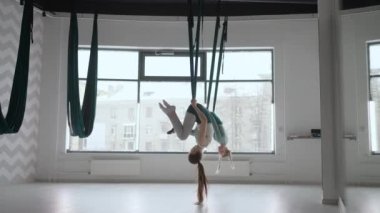 İki genç yogi kadın spor salonunda yeşil hamaklarda hava yogası yapıyorlar. Güzel kadınlar sınıfta çalışıyor, aero yogası yapıyorlar. Parsvottanasana, Piramit pozu