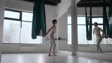 Genç ve güzel bir kadın, salıncakta sallanıyor. Genç bir kadın, hava yogası için hamakta kafasını ters çeviriyor. Odaklanmış olgun bir kadın spor salonunda hava yogası yapıyor.