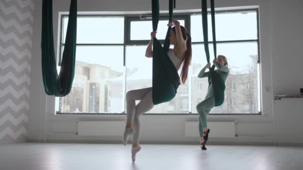 Le tir intérieur d'un deux femmes pratique le yoga antigravité d'inversion différente avec un hamac dans le studio de yoga. L'équilibre entre mental et physique, l'effort de deux personnes et le concept de réalisation — Video