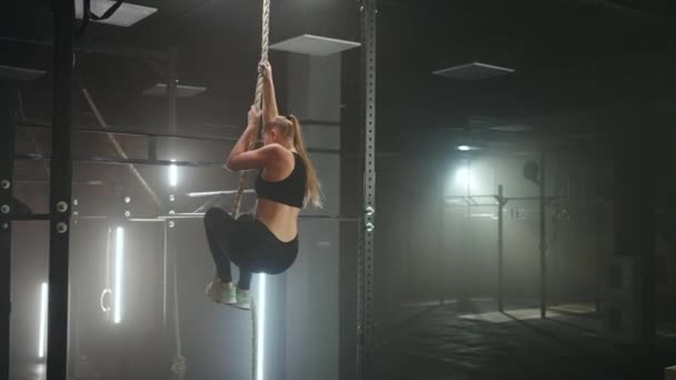 Volledige groothoekfoto van een vrouw die touwbeklimmingen uitvoert in de sportschool. Atletiek gezonde samenstelling. Kruisconditie. Bepaald atletische vrouw verplaatsen van het touw in een sportschool. — Stockvideo