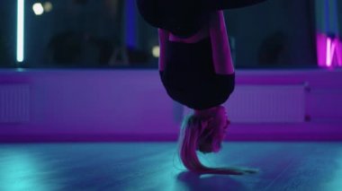 Baş aşağı asılı duran ve yoga hamağı salıncağı kullanan bir kadın yerçekimi yogası yapıyor. Yerçekimi yogası pozu vermek için hamak kullanan güzel genç bir kadının arka görüntüsü.