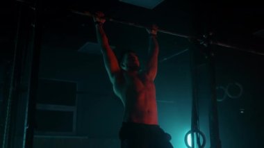 Genç sporcu spor salonunda barfiks barfiks egzersizi yapıyor. Genç sporcu spor salonunda barfiks barfiks egzersizi yapıyor. Yavaş çekim renk ışığı