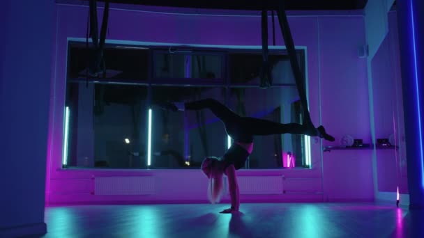 한 여자가 네온등을 켜고우아 한 운동을 하고 스트레칭 과느린 동작으로 춤을 추는 해먹 위 에서 스 포오츠 요가 를 한다. — 비디오