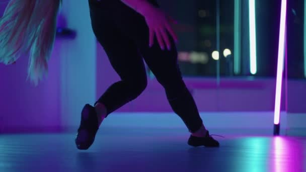 Een vrouw doet yoga en strekt zich uit op een hangende hangmat in neon licht. Een vrouw vliegt in een hangmat in de studio aan het stretchen en lichaamsoefeningen. Oefeningen in de lucht — Stockvideo