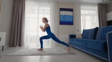 Öğleden sonra evde yoga yaparken halıda, kanepenin yanında ve oturma odasındaki TV 'de. Sabah egzersizleri ve yoga dersleri. Denge ve dayanıklılık için karmaşık yoga egzersizleri