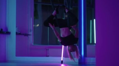 Baş aşağı asılı duran ve yoga hamağı salıncağı kullanan bir kadın yerçekimi yogası yapıyor. Yerçekimi yogası pozu vermek için hamak kullanan güzel genç bir kadının arka görüntüsü.