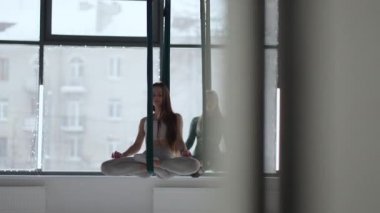 İki genç kadın hamakta sallanıyor ve nefesleri üzerinde meditasyon yapıyorlar. Aero Yoga