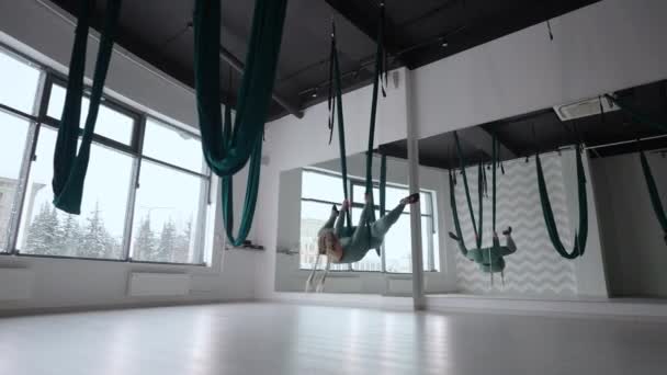 Mladá krásná žena cvičí na houpací síti z letecké jógy. Žena v odpoledních hodinách před zrcadlem v hale vystupuje protáhnout sám — Stock video