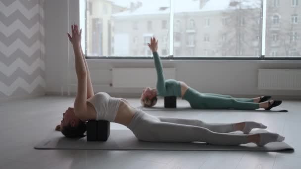 Deux jeunes femmes minces effectuent des exercices de dos couchés sur des plates-formes en cubes. étirement et tonus des muscles du dos. Amélioration de la posture — Video