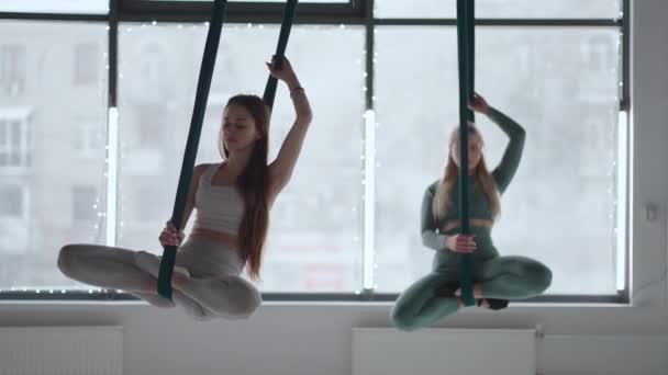 Two young women swing on hammocks and meditate concentrating on their breath. Aero Yoga — Stock Video
