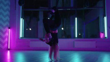 Baş aşağı asılı duran ve yoga hamağı salıncağı kullanan bir kadın yerçekimi yogası yapıyor. Yerçekimi yogası pozu vermek için hamak kullanan güzel genç bir kadının arka görüntüsü.