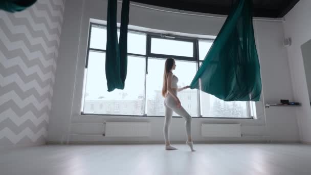 Een jonge vrouw in slow motion bereidt zich voor op een stretching en yoga les te beginnen op een hangmat. Rechtop de zich ontwikkelende hangmat weefsel voor de training — Stockvideo
