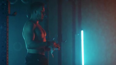 Ağır çekimde ip atlayan bir adam. Vücut geliştiren adam karanlık ve modern bir haçla ipin üstüne atlıyor.
