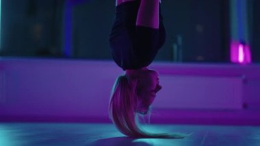 Baş aşağı asılı duran ve yoga hamağı salıncağı kullanan bir kadın yerçekimi yogası yapıyor. Yerçekimi yogası pozu vermek için hamak kullanan güzel genç bir kadının arka görüntüsü.