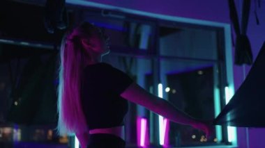 Genç, gülümseyen kadın salıncakta sallanıyor. Havadan uçan yoga egzersizleri fitness kulübündeki yeşil hamakta pratik yapıyor.