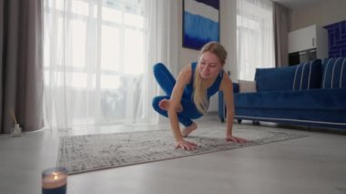 Evde bir kadın evden çıkmadan yoga egzersizleri yapıyor. Evde eğitim. Mavi takım elbiseli bir kadın halıda antrenman yapıyor.