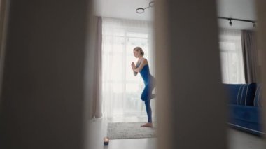 Öğleden sonra evde yoga yaparken halıda, kanepenin yanında ve oturma odasındaki TV 'de. Sabah egzersizleri ve yoga dersleri. Denge ve dayanıklılık için karmaşık yoga egzersizleri
