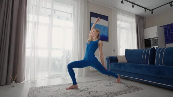 Latihan yoga di rumah di karpet di sore hari dekat sofa dan TV di ruang tamu. Latihan pagi dan kelas yoga. Latihan yoga kompleks untuk keseimbangan dan ketahanan — Stok Video