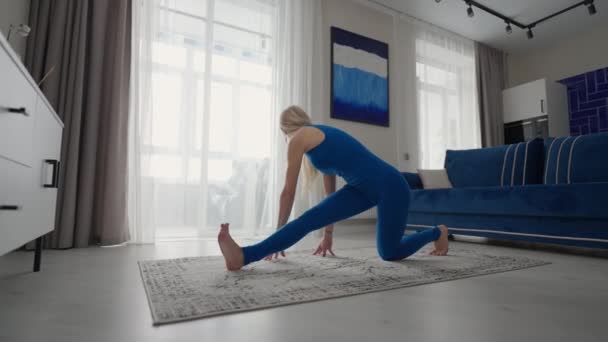 Rester à la maison en quarantaine et travailler à distance de la maison, une femme s'entraîne et fait des exercices d'équilibre tout en se tenant debout sur le tapis. vêtements de sport faire de l'exercice brûler les calories de graisse force d'entraînement — Video