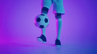 Zenci bir oyuncu karanlık bir stüdyoda, yerde neon ışıkları ve yavaş çekimde kırmızı ve mavi ışık efektleri olan bir futbol topuyla hokkabazlık yapar. Afrikalı profesyonel futbolcu